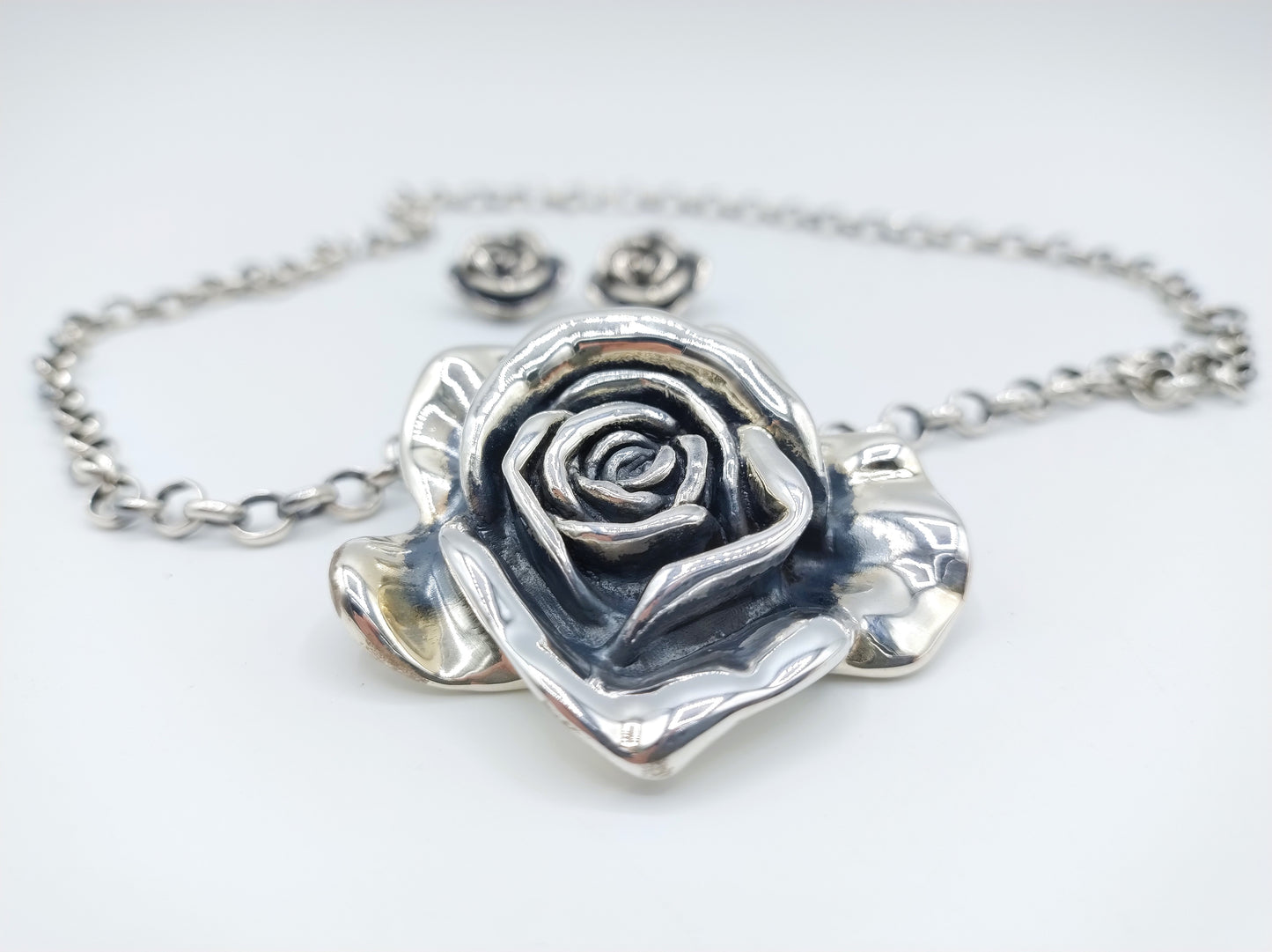 Jasseron-Kette mit silbernem Rosenanhänger und Ohrringen.