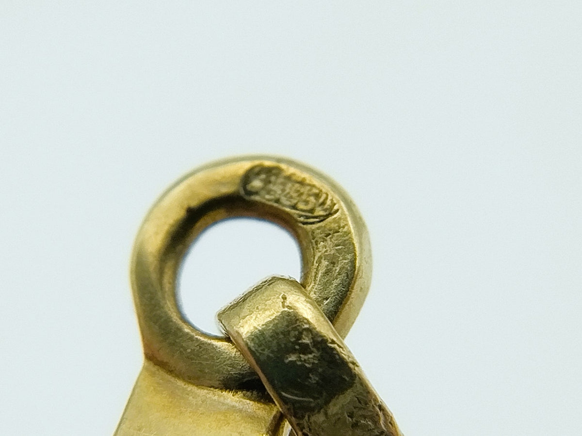 Close-up van gouden ring-oogje met ingehaakte bevestiging aan kruishanger