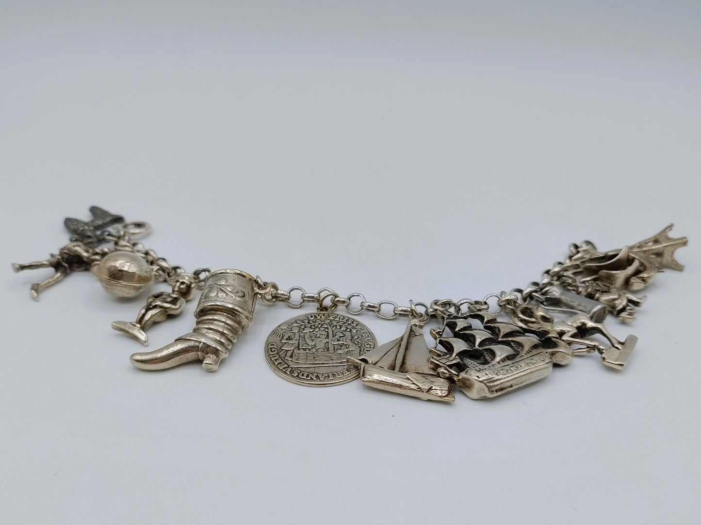 Zilveren bedelarmband met 13 bedels, o.a. penning uit 1766, 17 cm