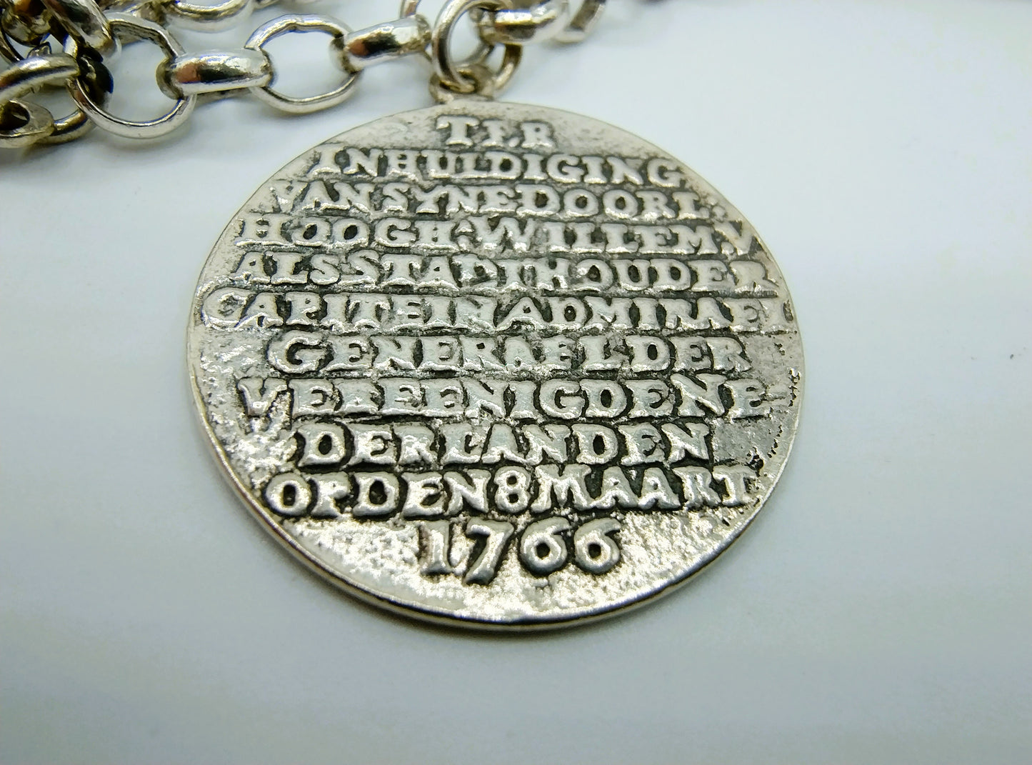 Zilveren bedelarmband met 13 bedels, o.a. penning uit 1766, 17 cm