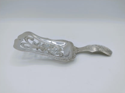 Zilveren natfruitschep in profiel met decoratieve rand en gebogen steel, glanzend