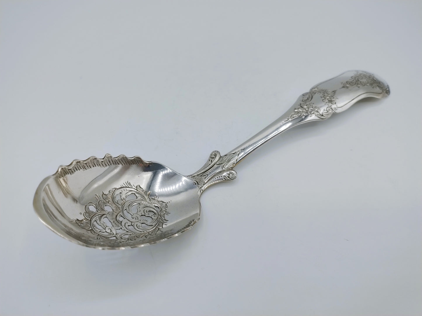 Zilveren natfruitschep met decoratieve rand en gegraveerde steel
