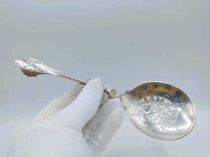 Zilveren natfruitschep vastgehouden met handschoen; ovale kom met sierlijke gravure.
