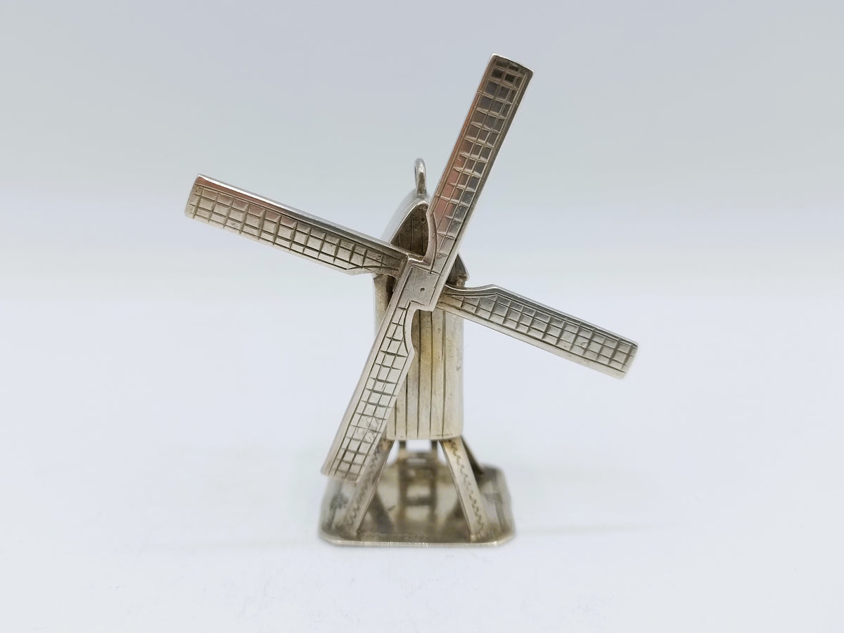 Zilveren miniatuur windmolen met vier wieken en ronde voet.