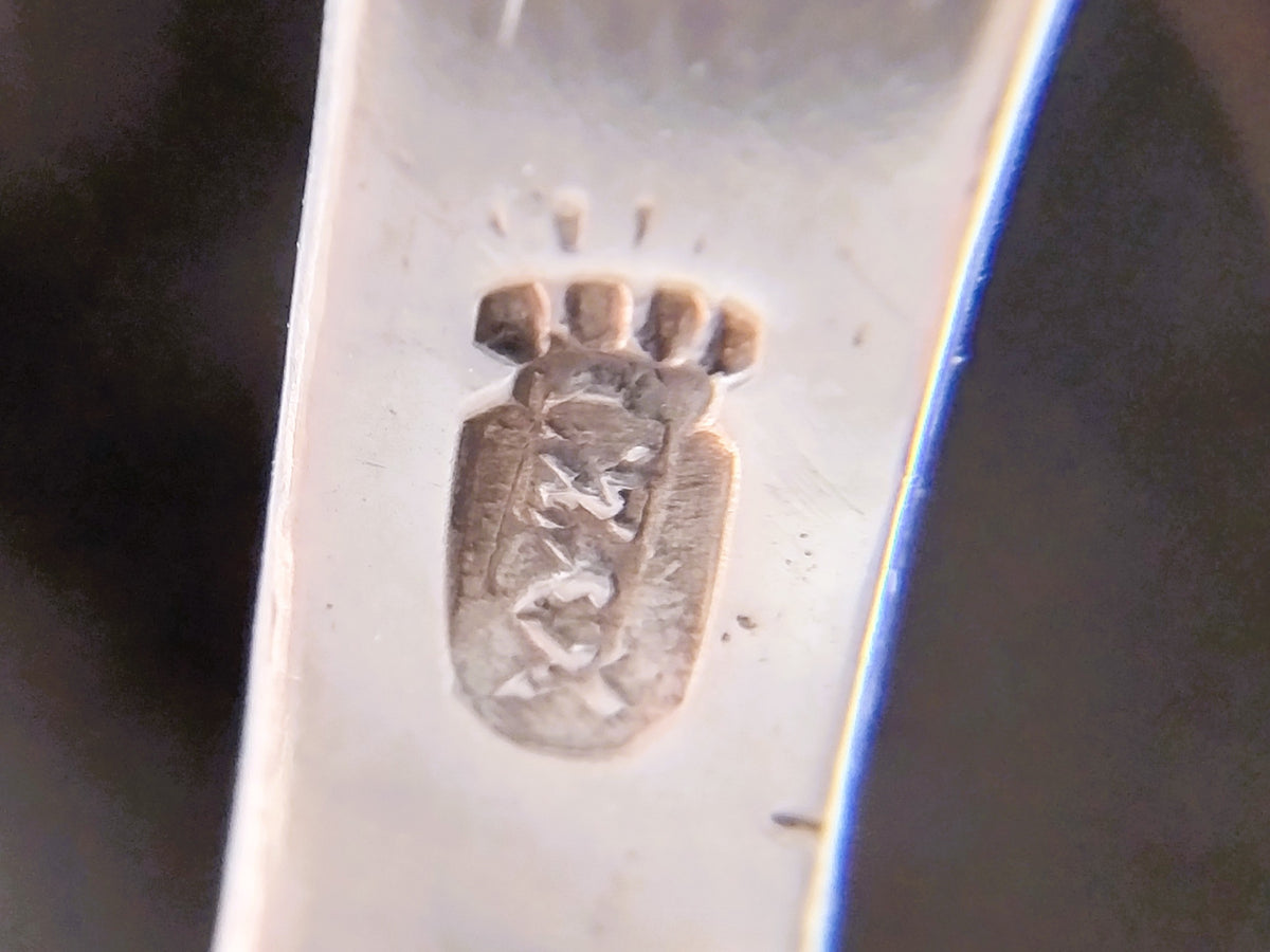 Stempel op zilveren plaatje van miniatuurwindmolen, close-up.