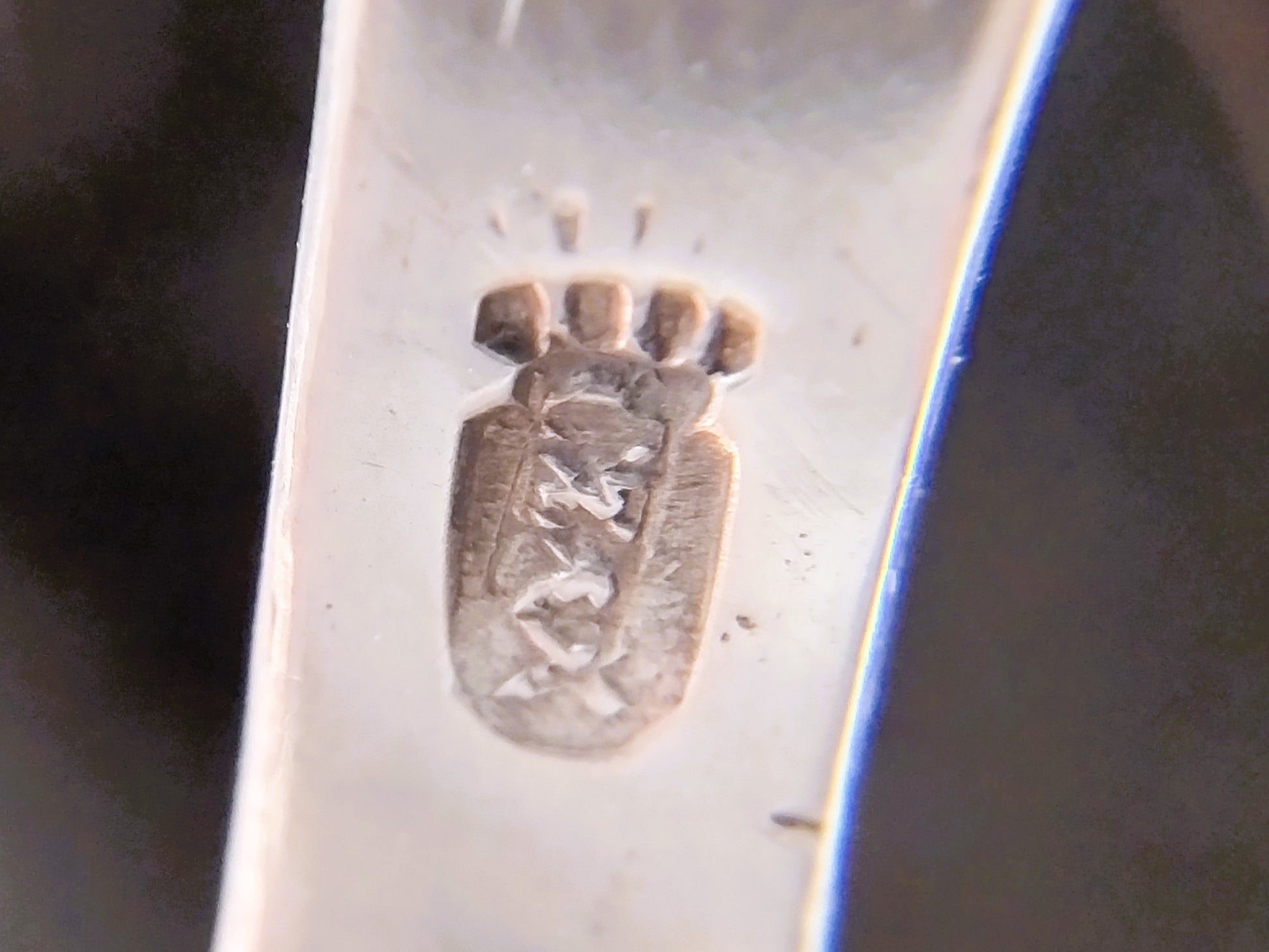 Stempel op zilveren plaatje van miniatuurwindmolen, close-up.