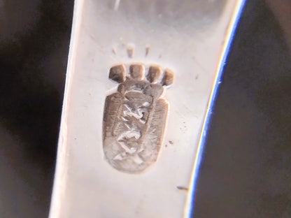 Stempel op zilveren plaatje van miniatuurwindmolen, close-up.