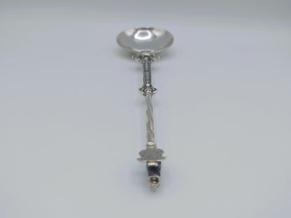 Zilveren sierlepel met bewerkte knop en verticale steel met knopvormig uiteinde