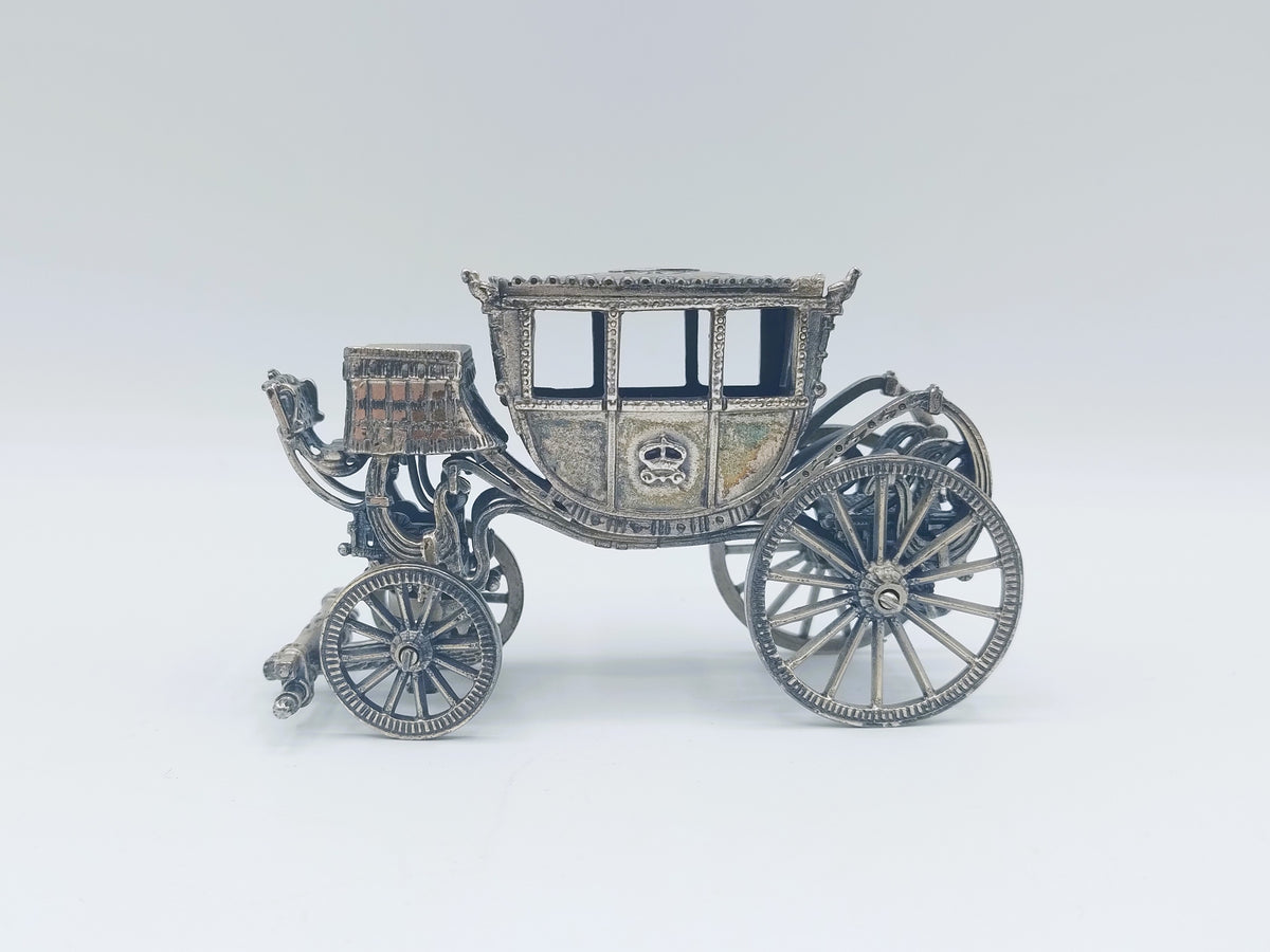Zilverkleurige miniatuurkoets met open rijtuig en vier sierlijke wielen
