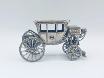 Zilverkleurige miniatuurkoets in zijaanzicht met open cabine en ronde spaakwielen