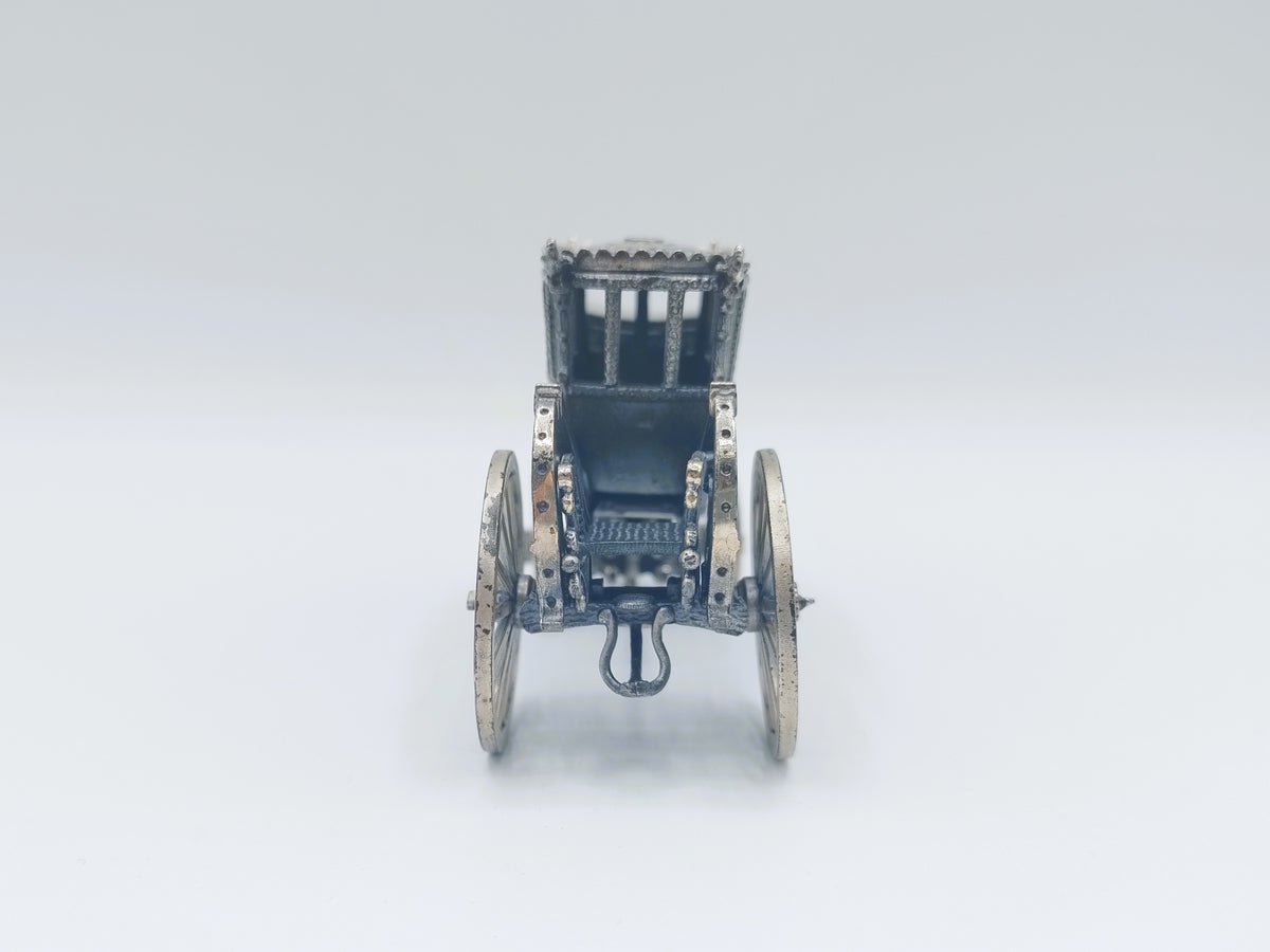 Zilverkleurige miniatuurkoets frontaal gezien met metalen opbouw en wielen