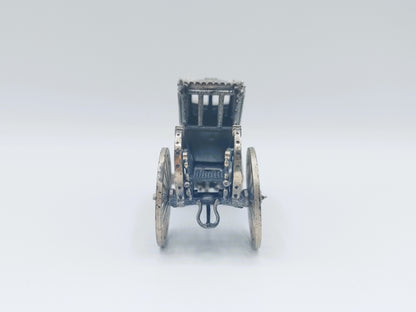 Zilverkleurige miniatuurkoets frontaal gezien met metalen opbouw en wielen