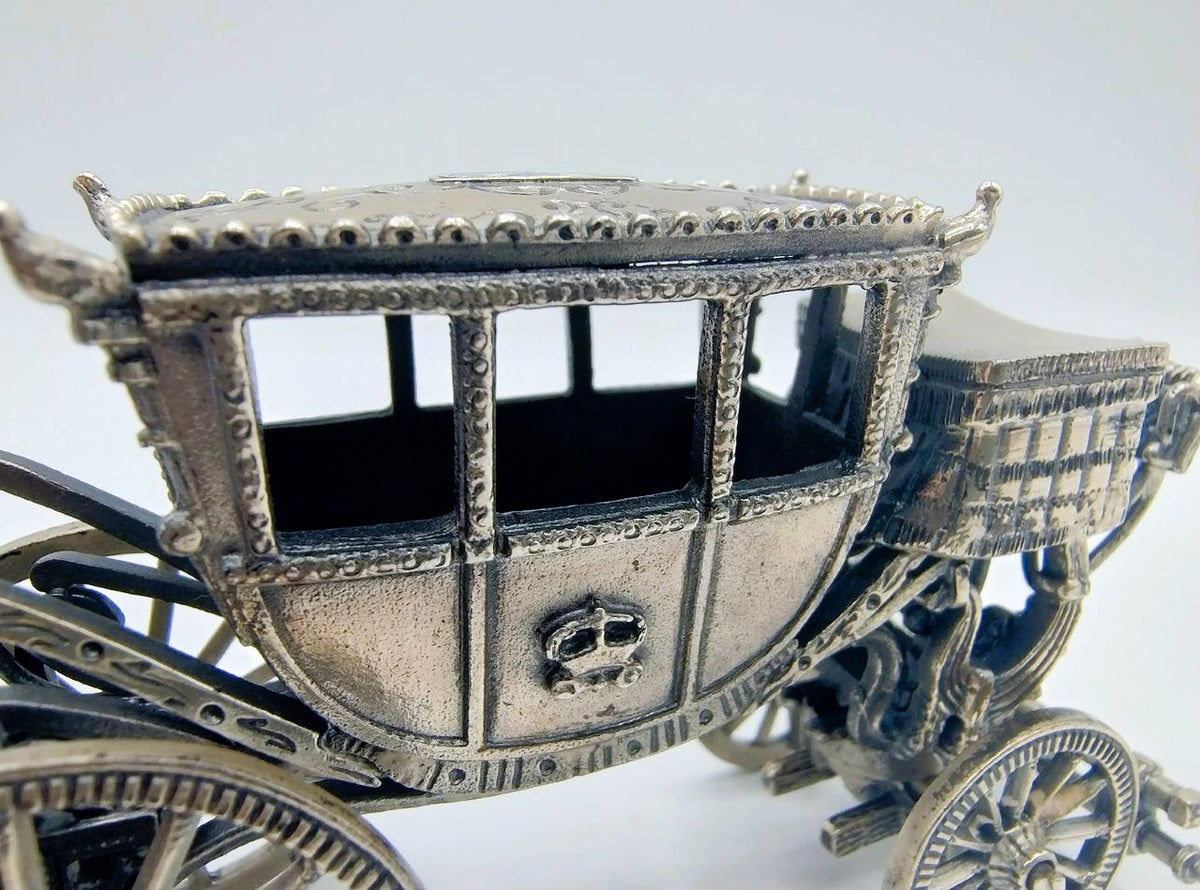 Zilverkleurige miniatuurkoets close-up: open ramen, gegraveerde carrosserie en wielen