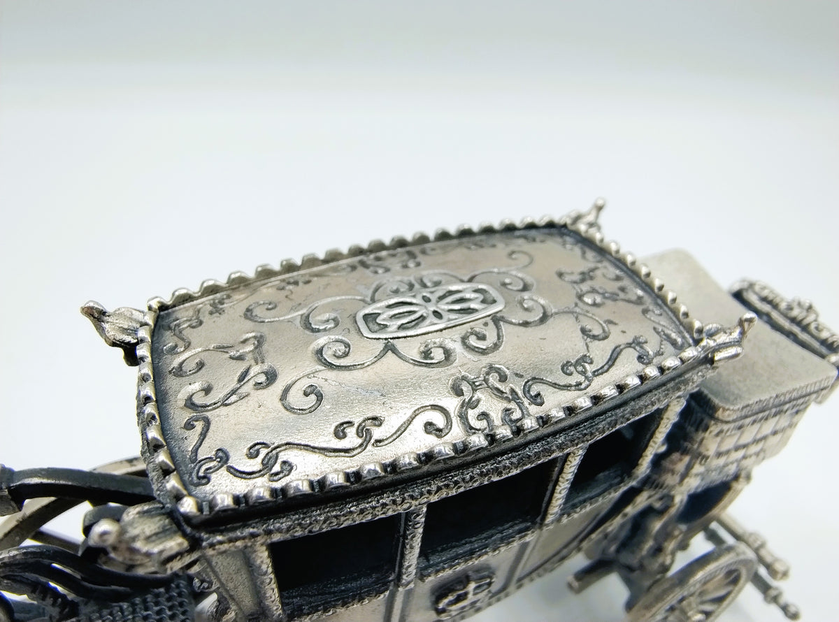 Zilverkleurige miniatuurkoets close-up van dak met sierlijke gravures