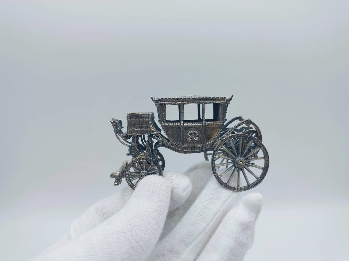 Zilveren miniatuurkoets met twee grote wielen en gedetailleerde koetsbak