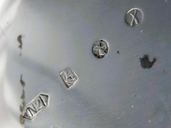 Zilveren parfumfles met gegraveerde merken op metalen plaat