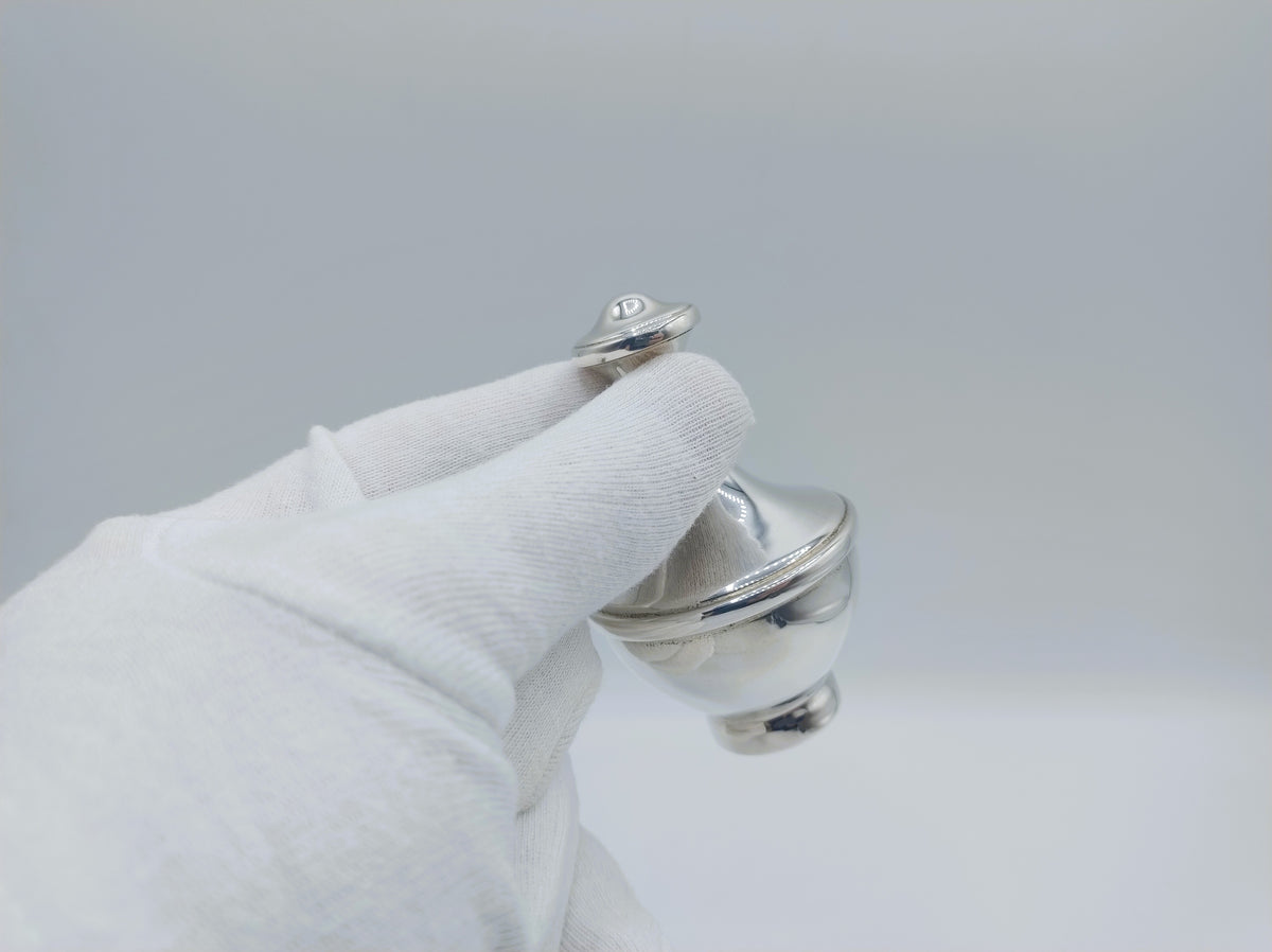 Zilveren parfumfles met dop, vastgehouden in witte handschoen