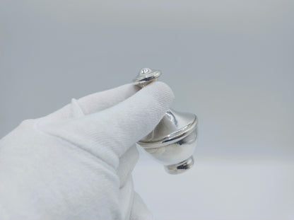 Zilveren parfumfles met dop, vastgehouden in witte handschoen