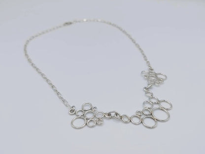 Close-up zilveren ketting met meerdere open ringen en fijne schakels