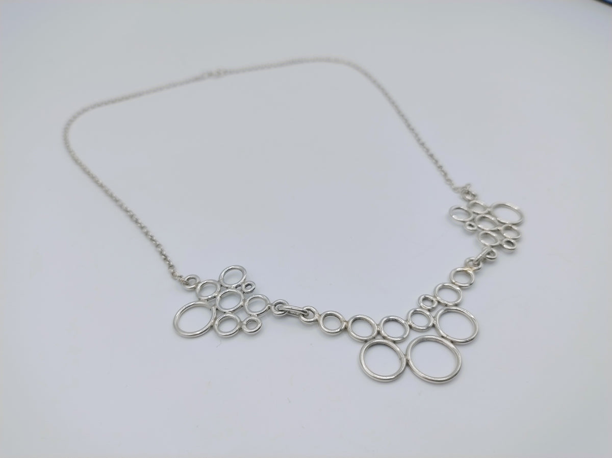 Zilveren ketting met ringvormige schakels, plat op witte ondergrond