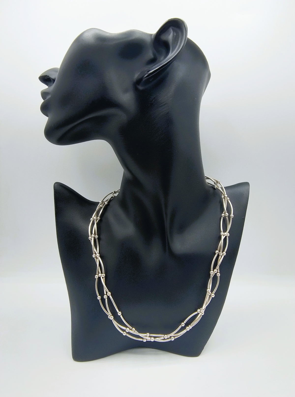 Zilveren designketting met drie rijen kettingschakels, als set op sierstandaard.