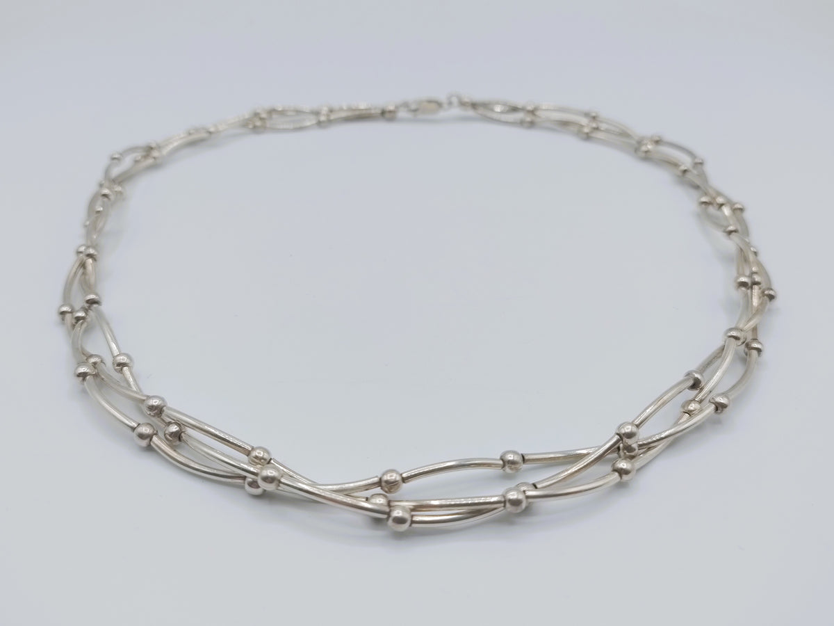 Zilveren ketting met drie rijen, ovale schakels en kleine verbindingsknooppjes.