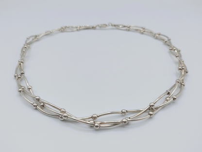 Zilveren ketting met drie rijen, ovale schakels en kleine verbindingsknooppjes.