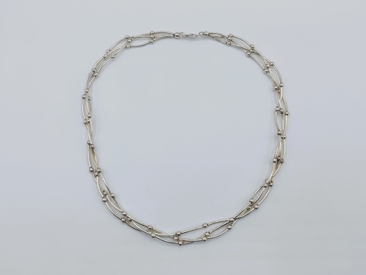Zilveren ketting met drie rijen, ovale en staafjeschakels met gladde details.
