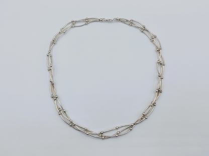 Zilveren ketting met drie rijen, ovale en staafjeschakels met gladde details.