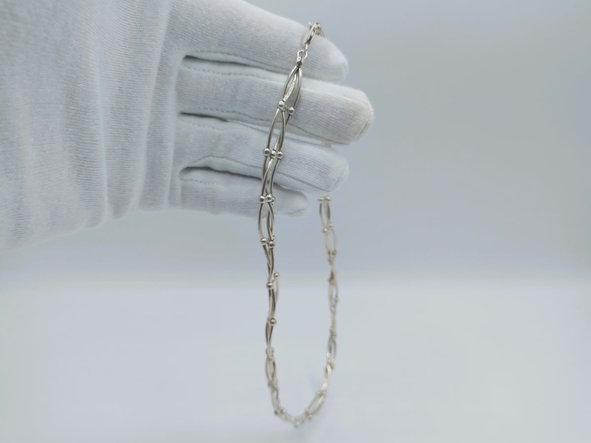 Zilveren ketting die neerhangt, drie rijen kettingschakels bij mouw.