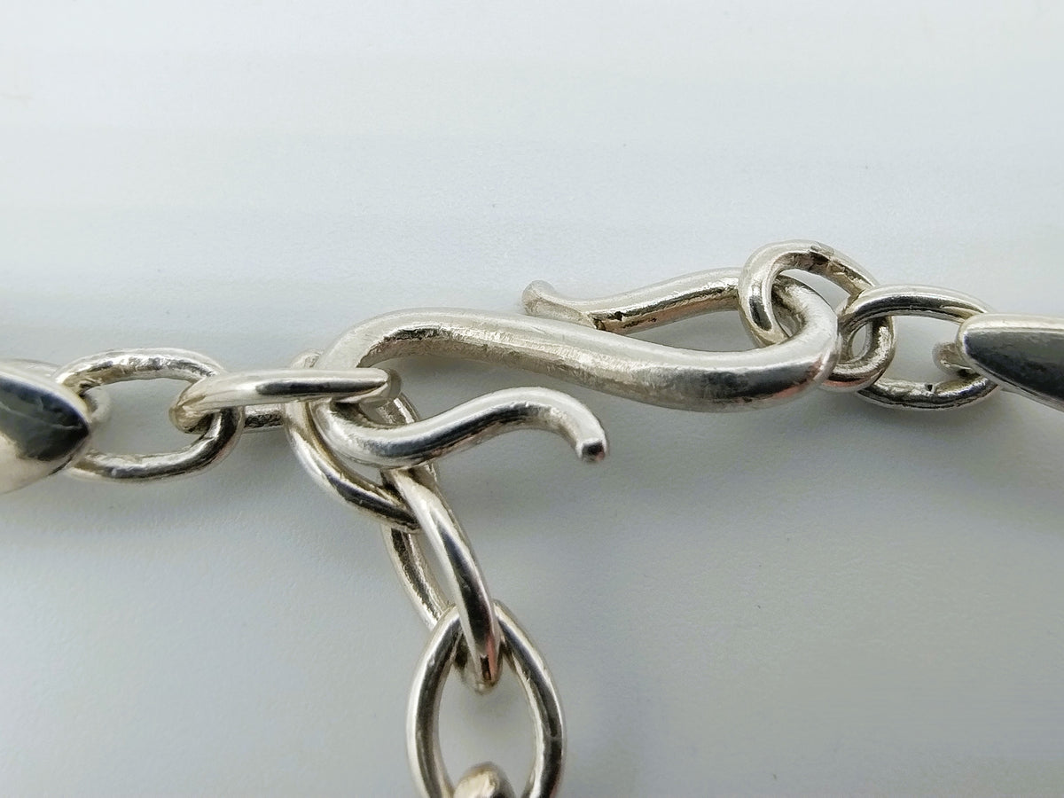 Zilveren schakeldetail met ringen en ovale plaatjes, onderdeel van de choker