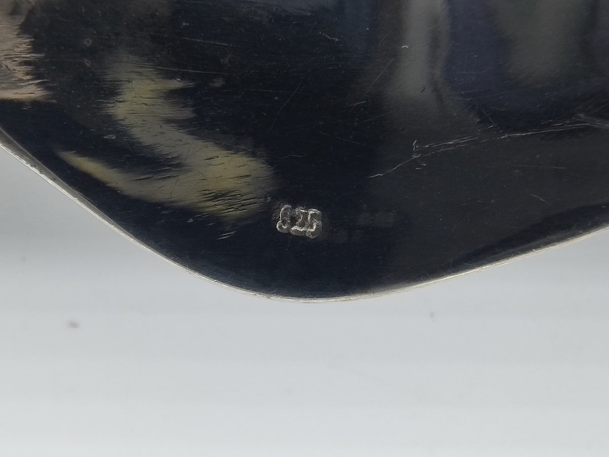 Zilveren collierdetail met keurmerk op metalen plaatje