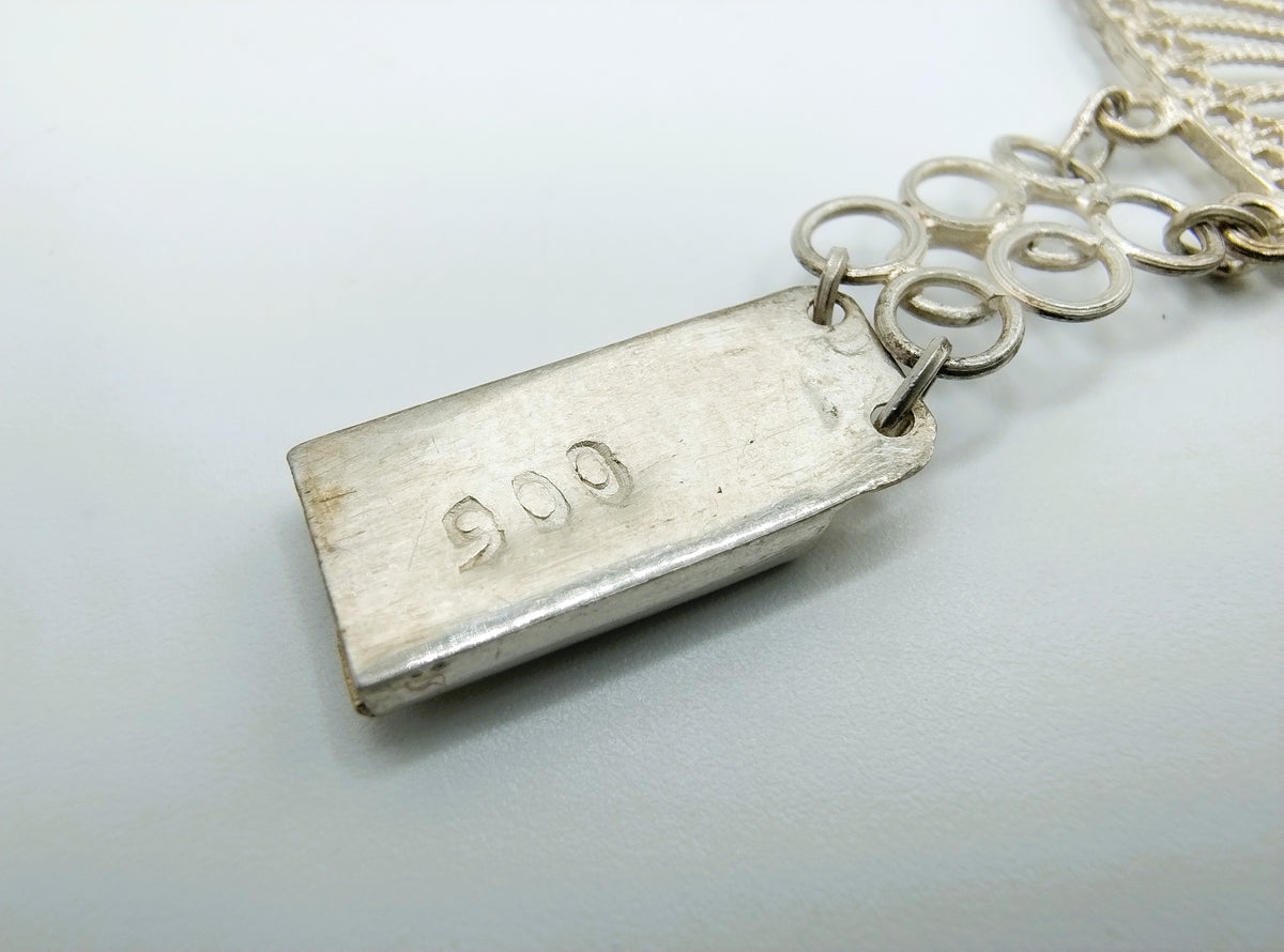 Zilveren armbanddetail met keurplaatje en ringetjes aan de ketting