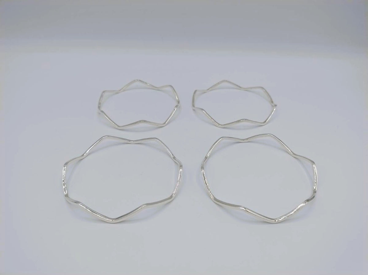 Vier zilverkleurige stervormige armbanden, losse bangle-stukken