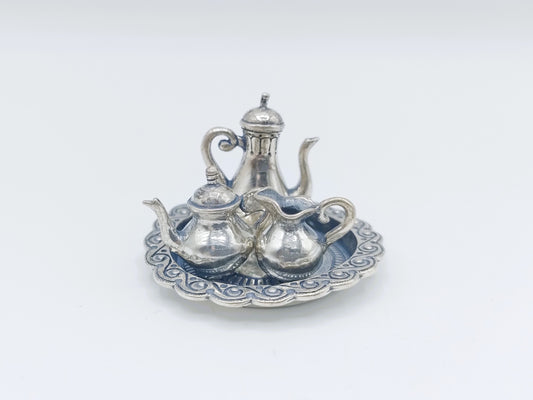 Miniatuur zilveren theeservies met kannetje en kopjes op sierlijke schotel