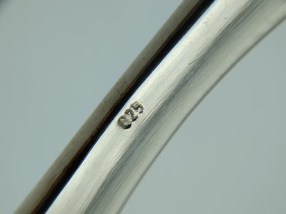Close-up van slavenarmband met ingeslagen 925 markering op zilver