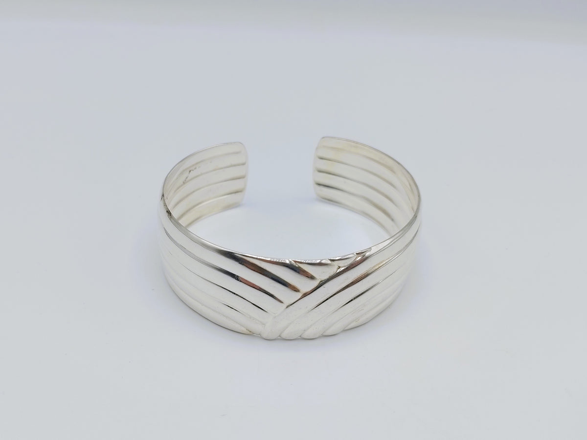 Zilveren cuff armband met golfmotief; gladde binnenkant en geribbelde buitenzijde.