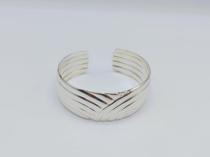 Zilveren cuff armband met golfmotief; gladde binnenkant en geribbelde buitenzijde.