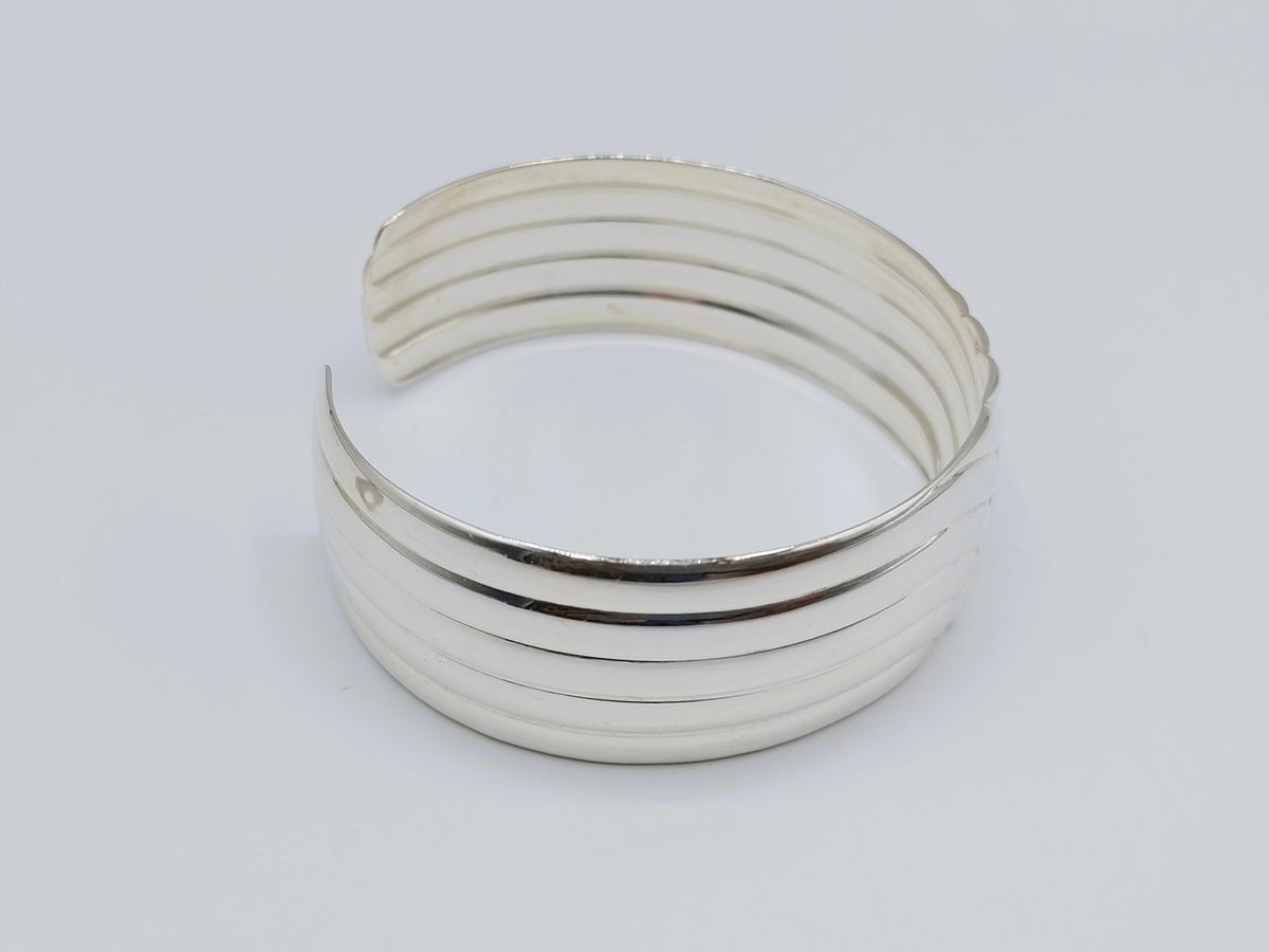 Zilveren cuff armband met golfmotief; meerdere horizontale groeven op de band.