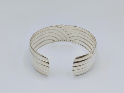Zilveren cuff armband met golfmotief; afgeronde uiteinden en gestreepte structuur.