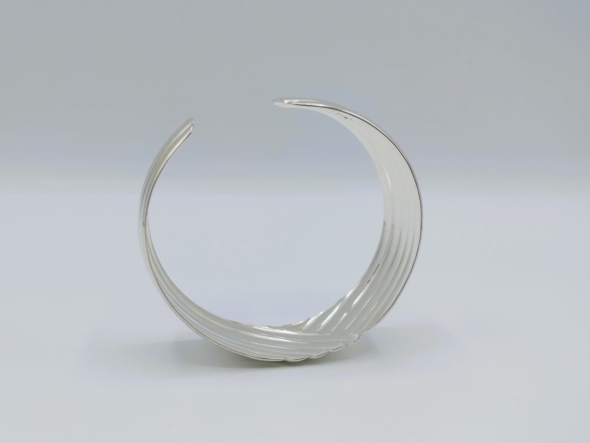 Zilveren cuff armband met golfmotief; open ronde band met gedetailleerde rijen.