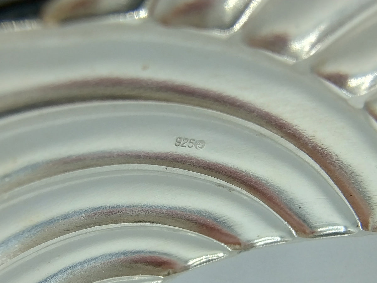 Close-up van zilveren armband met keurmerk “925” op het metaal.