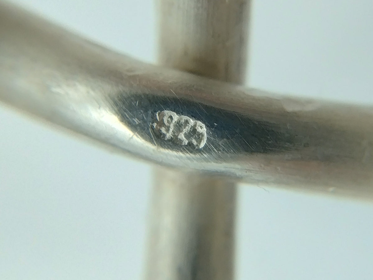 Zilveren armband-schakel met gegraveerd keurmerk, close-up van stempel op band
