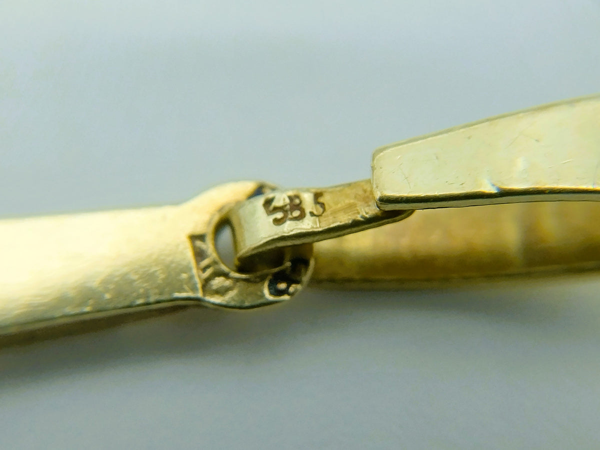 Detail van 585-keurmerk op gouden schakel van kruishanger