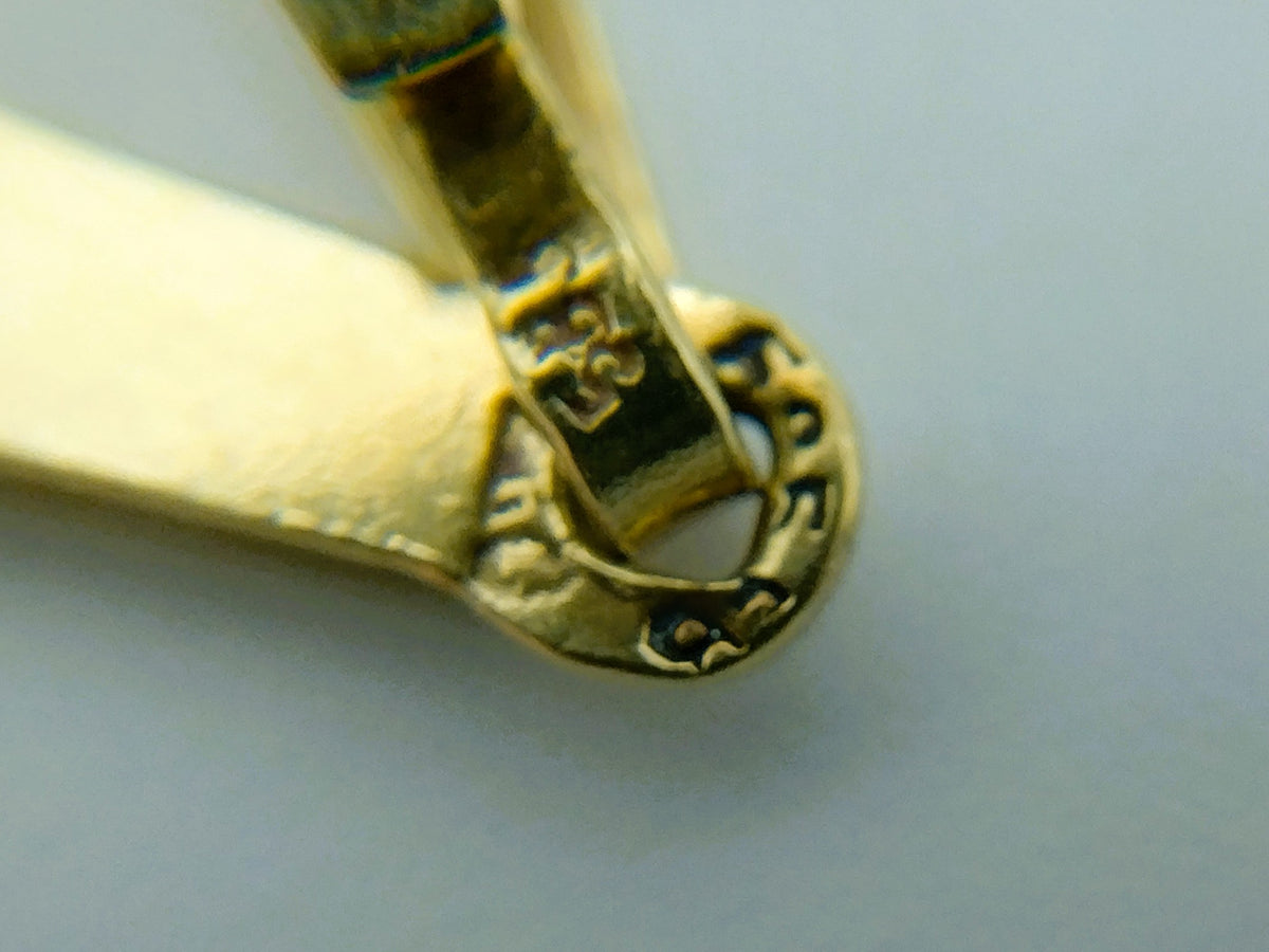 Detail van sluiting en hangerbevestiging op gouden kruishanger, met reliëf