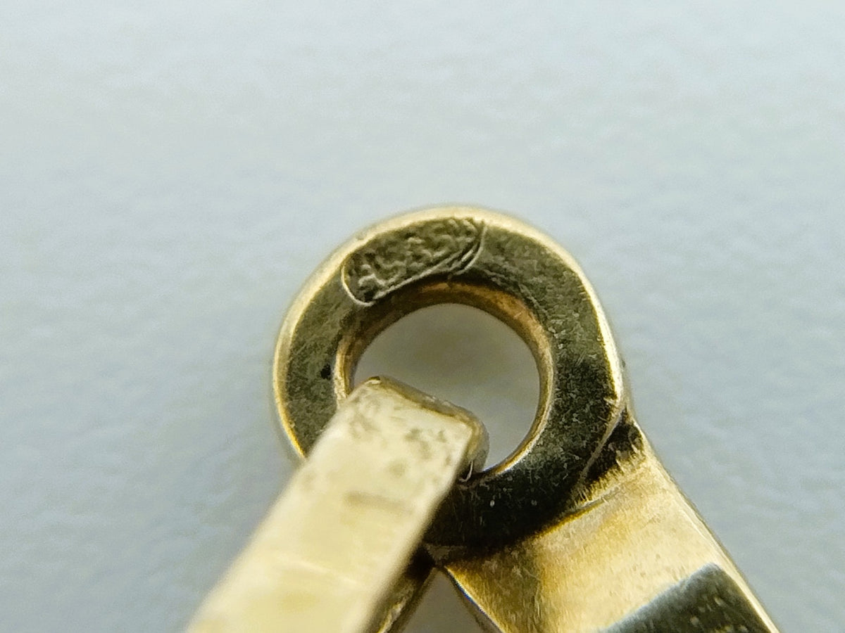 Close-up van gouden ophangoogje met bevestiging aan kruishanger