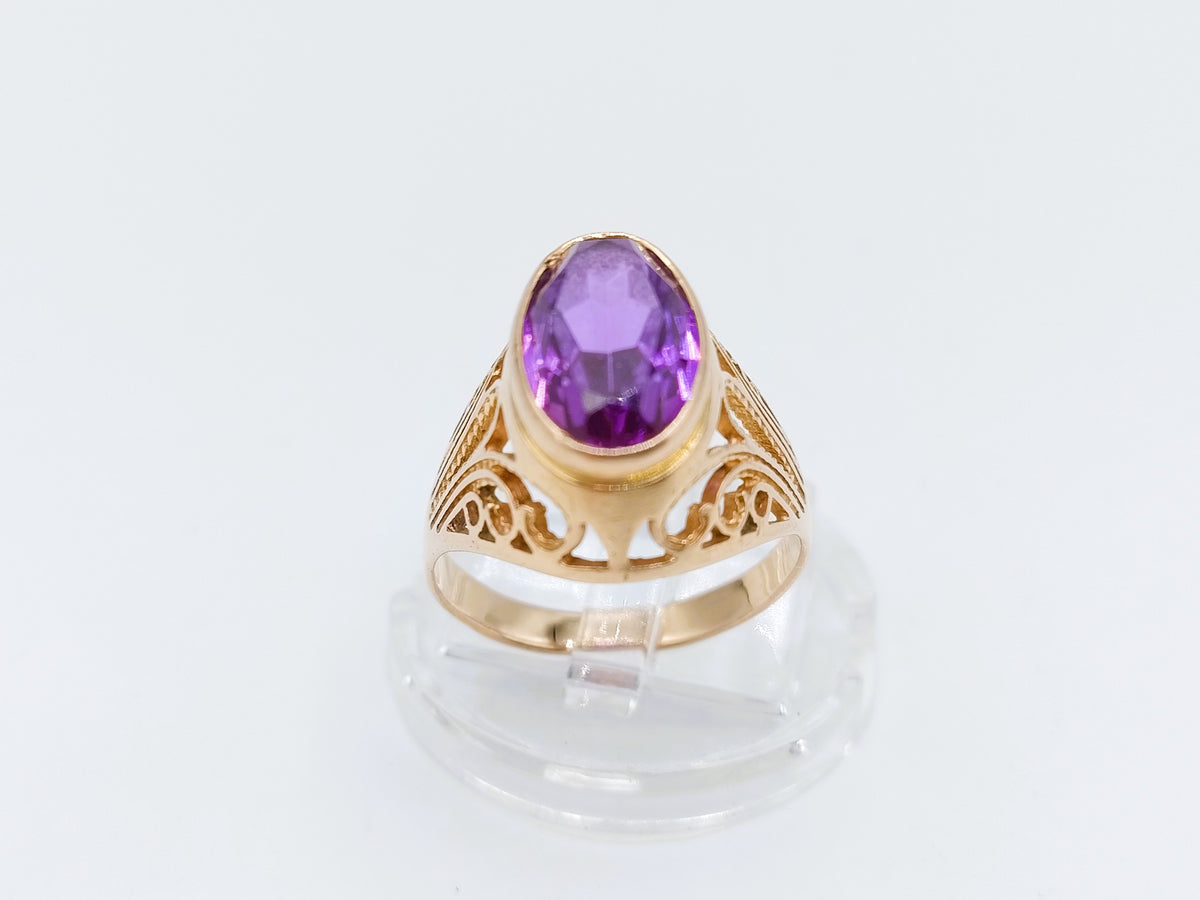 Gouden ring met ovale paarse amethist en decoratieve uitsnijdingen aan de band