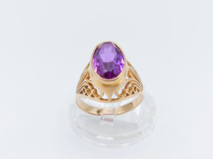 Gouden ring met ovale paarse amethist en decoratieve uitsnijdingen aan de band