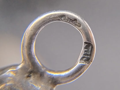 Close-up van een zilveren breipendop met ronde opening en gegraveerde rand