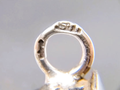 Close-up van zilveren breipendop-lus met ingeslagen stempelmarkering